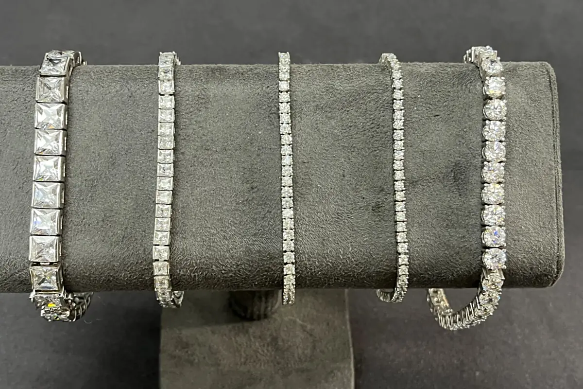 Diamond tennis and link bracelets draped over a velvet stand