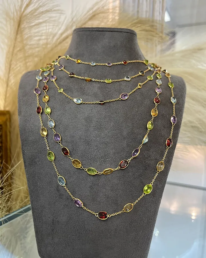 Layered multi-gemstone station necklaces on a velvet bust