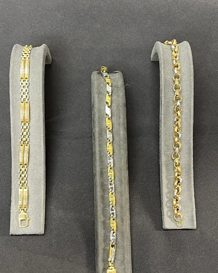 Three gold and two-tone bracelets on velvet display stands